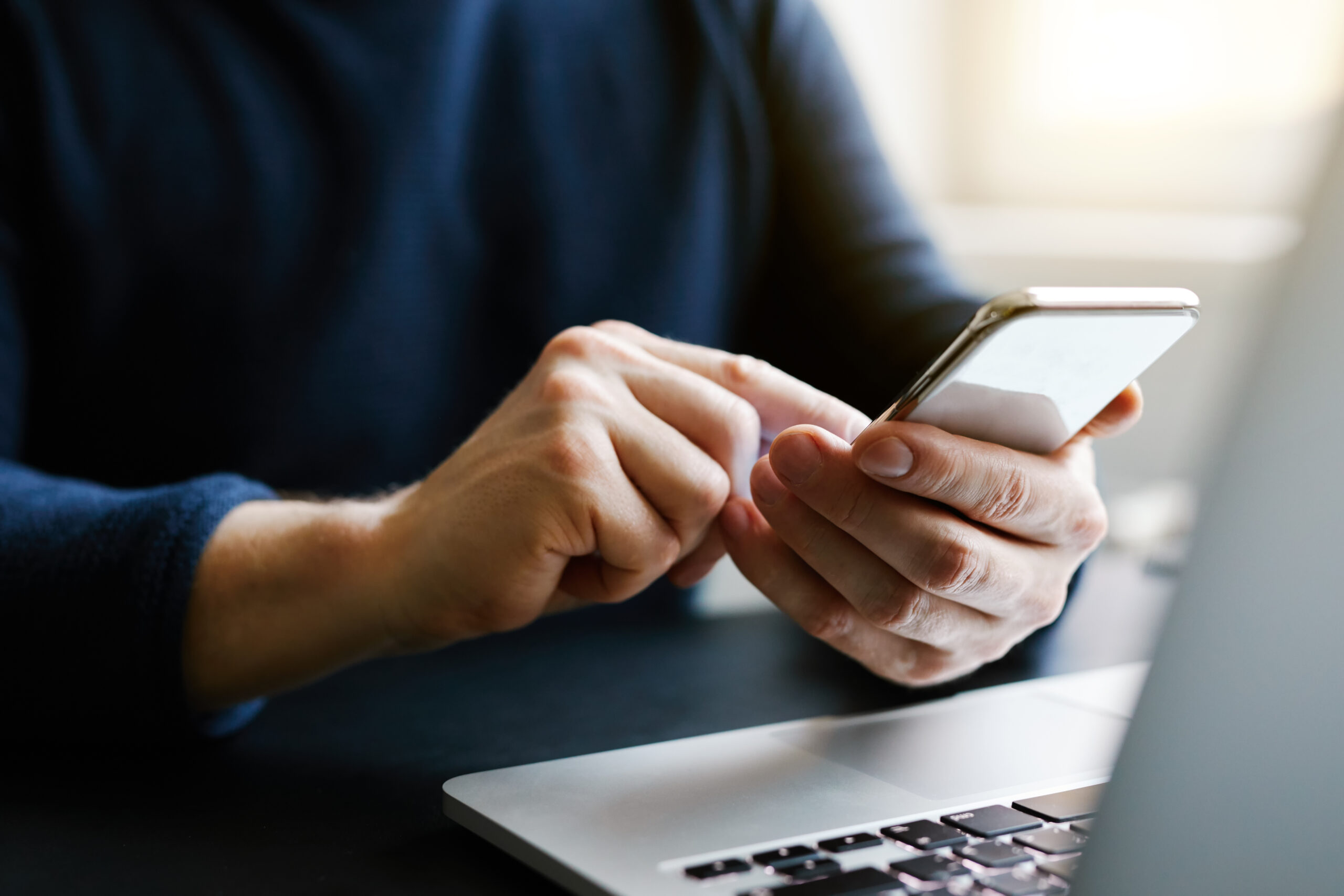 Man with a finger on the screen using a mobile phone in the offi